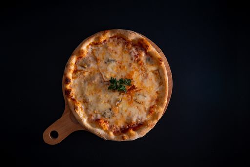 A top view of a freshly baked delicious cheesy pizza with parsley on a wooden cutting board