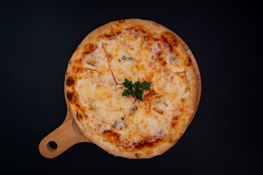 A top view of a freshly baked delicious cheesy pizza with parsley on a wooden cutting board