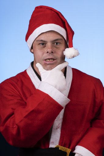 A young male with down syndrome posing in a Santa Claus costume isolated on a blue background