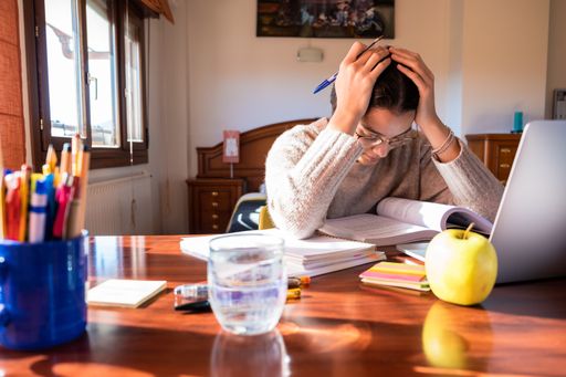 A young female student sitting on her desk in the bedroom, studying at home, the concept of home and remote education