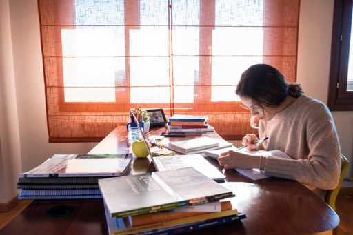 A young female student sitting on her desk in the bedroom, studying at home, the concept of home and remote education