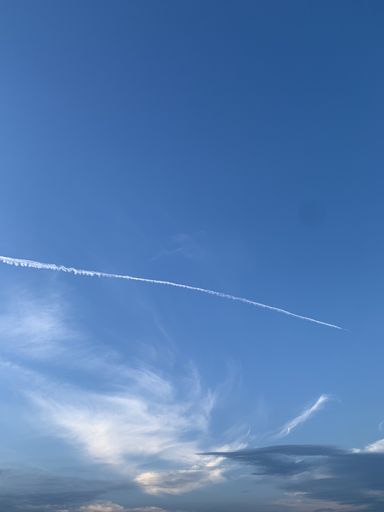 A vertical shot of plane tracks on a blue sky during a sunny day