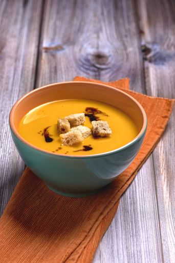 A vertical selective focus closeup of the soup in a bowl on a wooden table