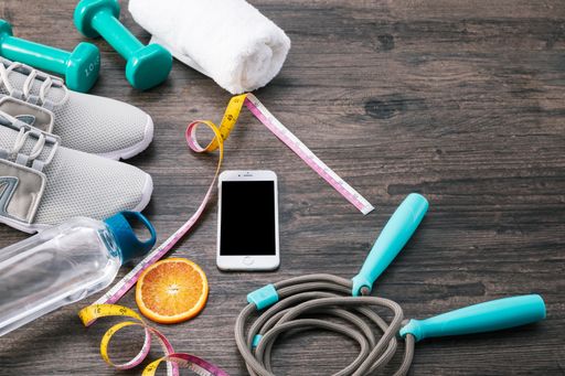 А fitness composition with a towel, dumbbells, sport boots, bottle, measuring tape, skipping rope