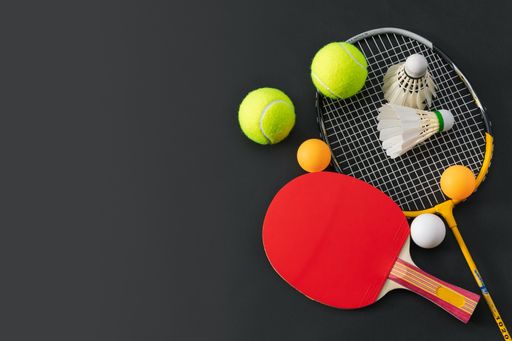 A high angle shot of ping pong balls and rackets on a black surface