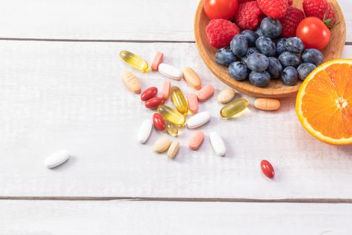 A top view of fresh fruits and vegetables with different medicine on a wooden table