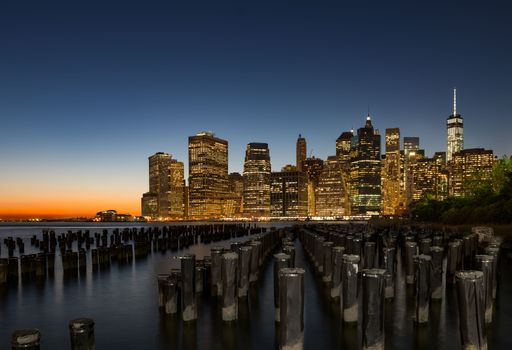 A stunning view of the majestic Manhattan skyline in New York City during the blue hour, featuring iconic skyscrapers illuminated against the sky