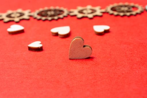 A selective focus shot of wooden heart figures on a red surfa