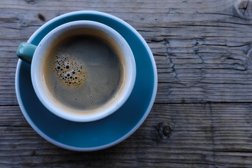 A top view of a cup of coffee on a wooden table