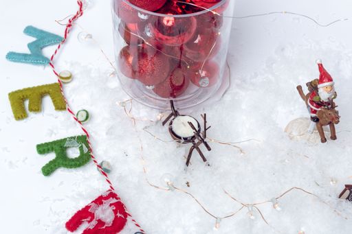 A beautiful shot of red Christmas balls in a transparent box and small toys on a white background
