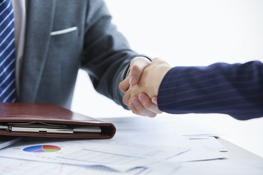 Two businessmen in elegant suits at a business meeting shaking hands in the office