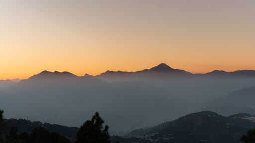 A beautiful winter sunset in the Garhwal Region of India, with the valley blanketed in a thick fog, creating a stunning and peaceful landscape