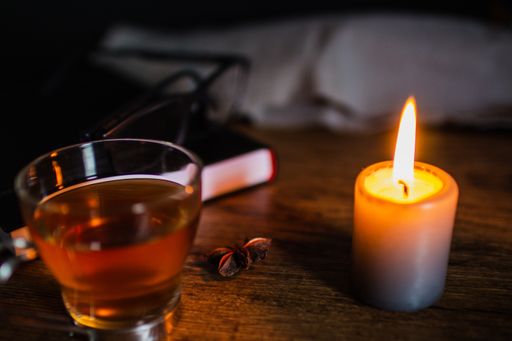 A high angle shot of star anise tea with a candle on a wooden table