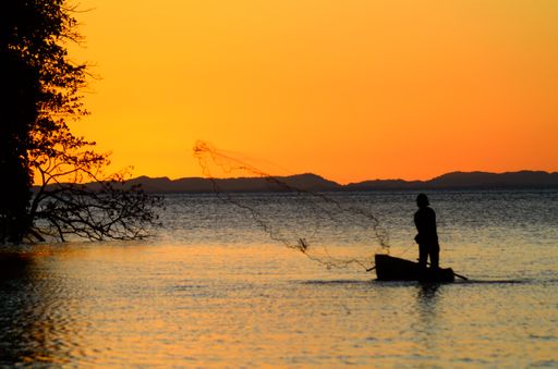 A silhouette of a person on a boat fishing in the sea during sunset in Ometepe, Nicaragua