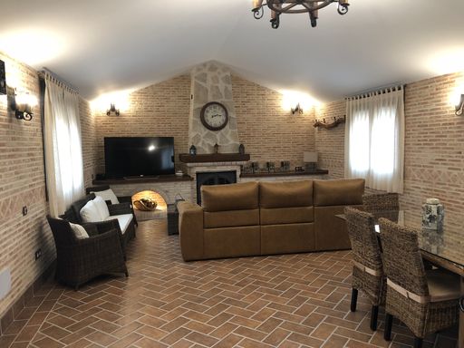 A modern rural living room interior with brick-made wall, comfortable furniture, and fireplace