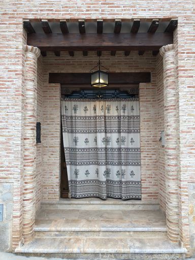 A vertical shot of a modern house facade with brick-made walls and a curtained doorwa