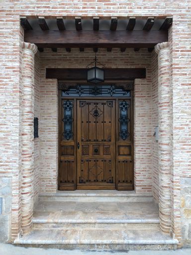 A vertical shot of a modern house facade with brick-made walls and a wooden doorway