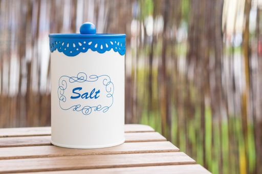 A closeup shot of a jar or container of salt on a wooden table