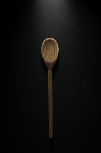 A vertical shot of a big wooden spoon isolated on black background