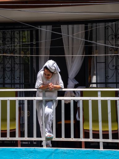 Medellin, Antioquia / Colombia - November 15 2020: Latin Woman with a Towel on her Head Looks at the Street from her Balcony