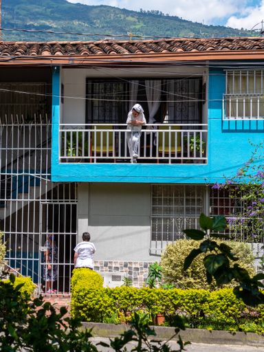 Medellin, Antioquia / Colombia - November 15 2020: Latin Woman with a Towel on her Head Looks at the Street from her Balcony