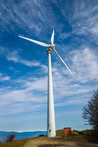 A vertical shot of a wind turbine under the cloudy sky