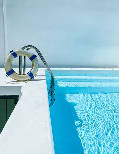 View of a crystal clear pool with steps and life guard buoy ring