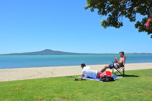 View of people at St Heliers Bay beach with Rangitoto Island in background