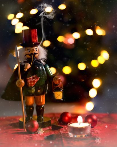 A vertical shot of a nutcracker near a burning candle on a Christmas background