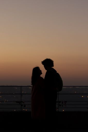 A silhouette of a romantic couple on the rooftop during sunset with the cityscape in the background