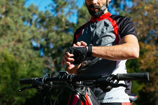 A closeup shot of a cyclist adjusting his watch before riding his bike