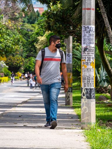 Medellin, Antioquia / Colombia - November 15 2020: Latin Male Passerby with Black Face Mask Walks on a Sunny Day