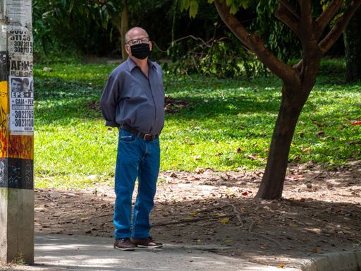 Medellin, Antioquia / Colombia - November 15 2020: Older Man Wearing Glasses and a Black Face Mask is Standing Looking at the Camera