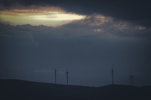 A scenic view of windmills on top of a hill during sunset