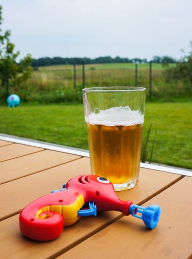 A vertical shot of a glass of beer and a red seahorse toy on the table