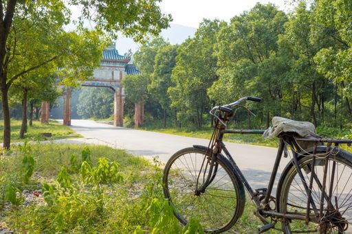 A view of an old rustic bike along the road near an ancient arc architecture