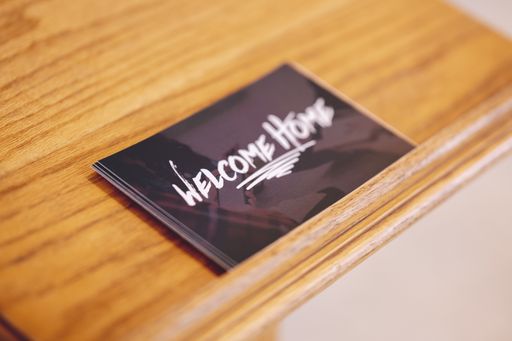 A selective focus shot of "Welcome Home" cards on a wooden table