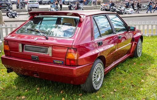 The view from behind of a red Lancia model Delta HF parked on the grass