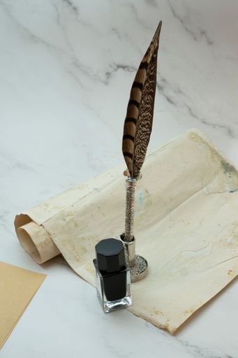 A closeup shot of a vintage parchment with ink and a quill pen