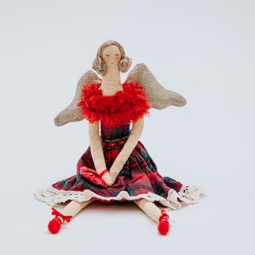 A soft Christmas toy in the shape of an elegant ballerina in a red dress with a checkered skirt