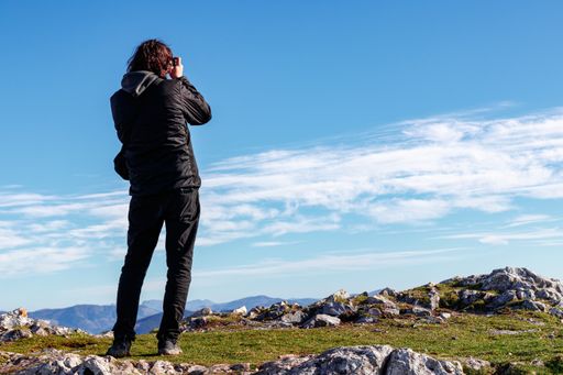 A low angle shot of a male taking pictures of a beautiful landscapes