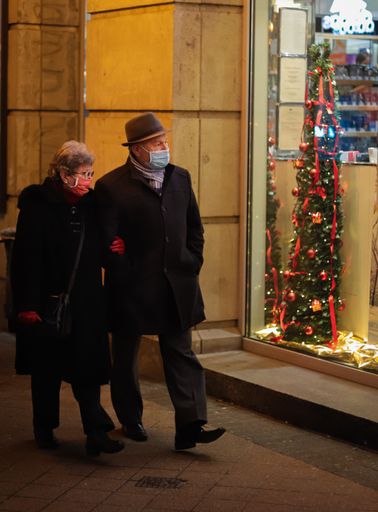 A vertical shot of an elderly couple walking in the street during the pandemic