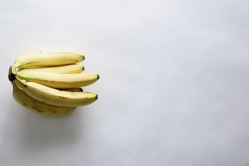 A high angle shot of fresh delicious bananas on a white surface with an empty space for text