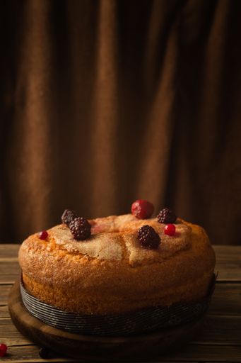A vertical shot of a delicious cake with red berries, strawberries, and blackberries