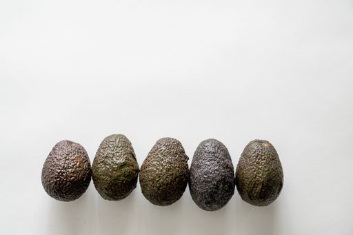 A lineup of fresh delicious avocados on a white surface with an empty space for text