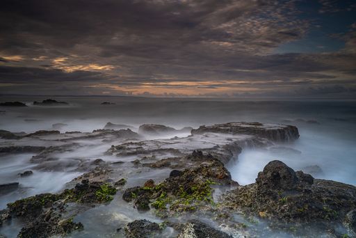 A breathtaking view of Karang Bokor Sawarna in Indonesia under dark cloudy sunset sky, long exposure