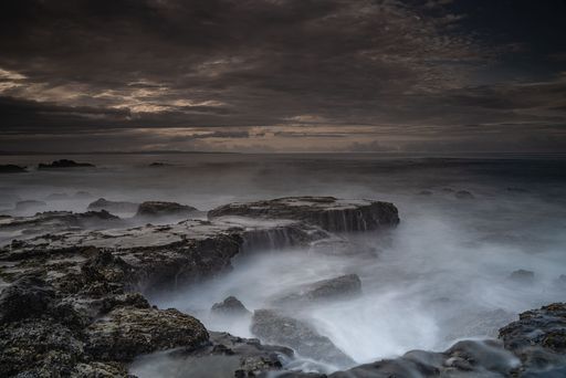 A breathtaking view of Karang Bokor Sawarna in Indonesia under dark cloudy sunset sky, long exposure