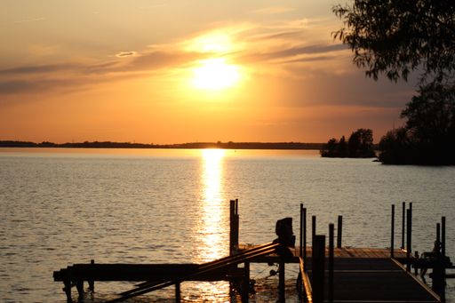 A scenic view of a wooden pier on a tranquil lake at golden sunset