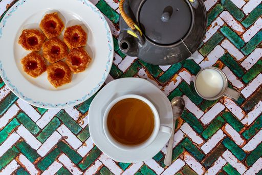 A still life with a cup of tea, teapot, sugar and cookies on the rustic table background