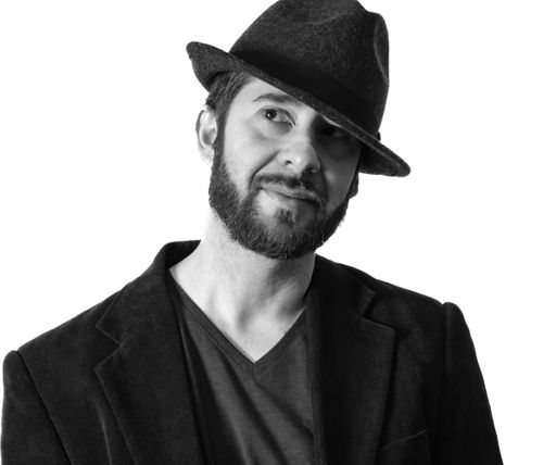 A grayscale shot of a handsome bearded male wearing a Fedora hat